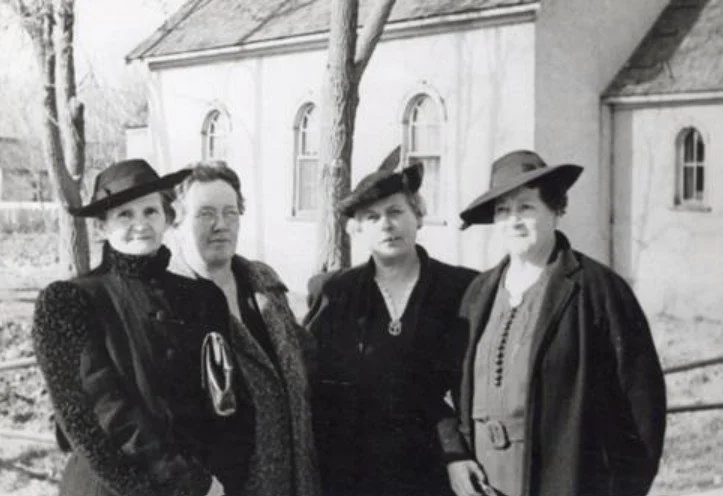 Photo of the Relief Society Presidency in front of the Lehi Relief Society Hall on Main Street. The Relief Society Hall is located on the north-west corner of Main and 2nd West. Right to left: Lucy Witman, Lulu Anderson, Lisa Logston, Della Fox.