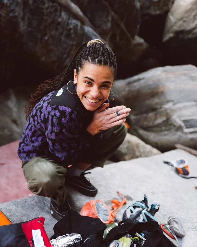 boulderer squatted on crashpad warming up fingers