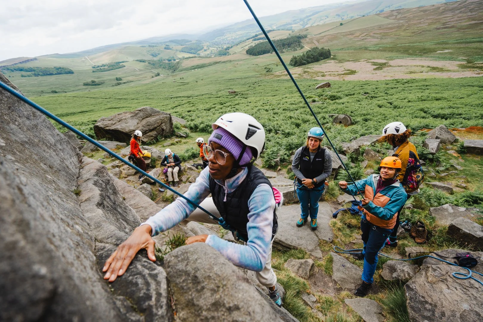 Climber on tope rope starts route with others looking on