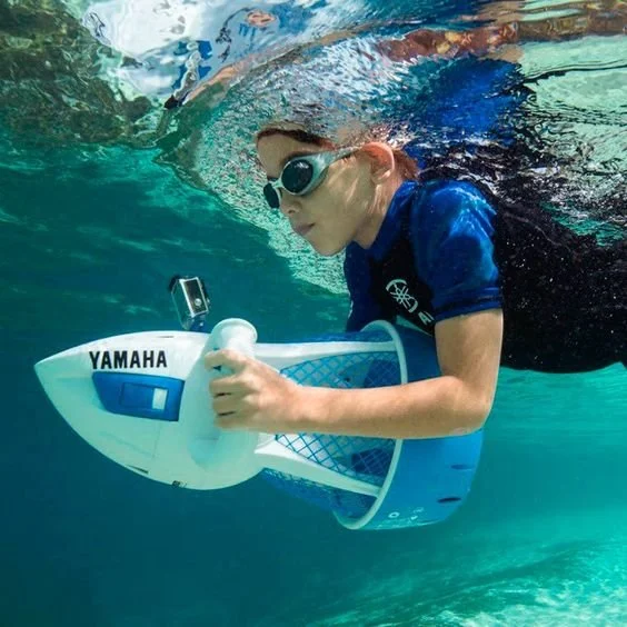 Girl swimming underwater with snorkel mask, holding a Yamaha underwater drone.