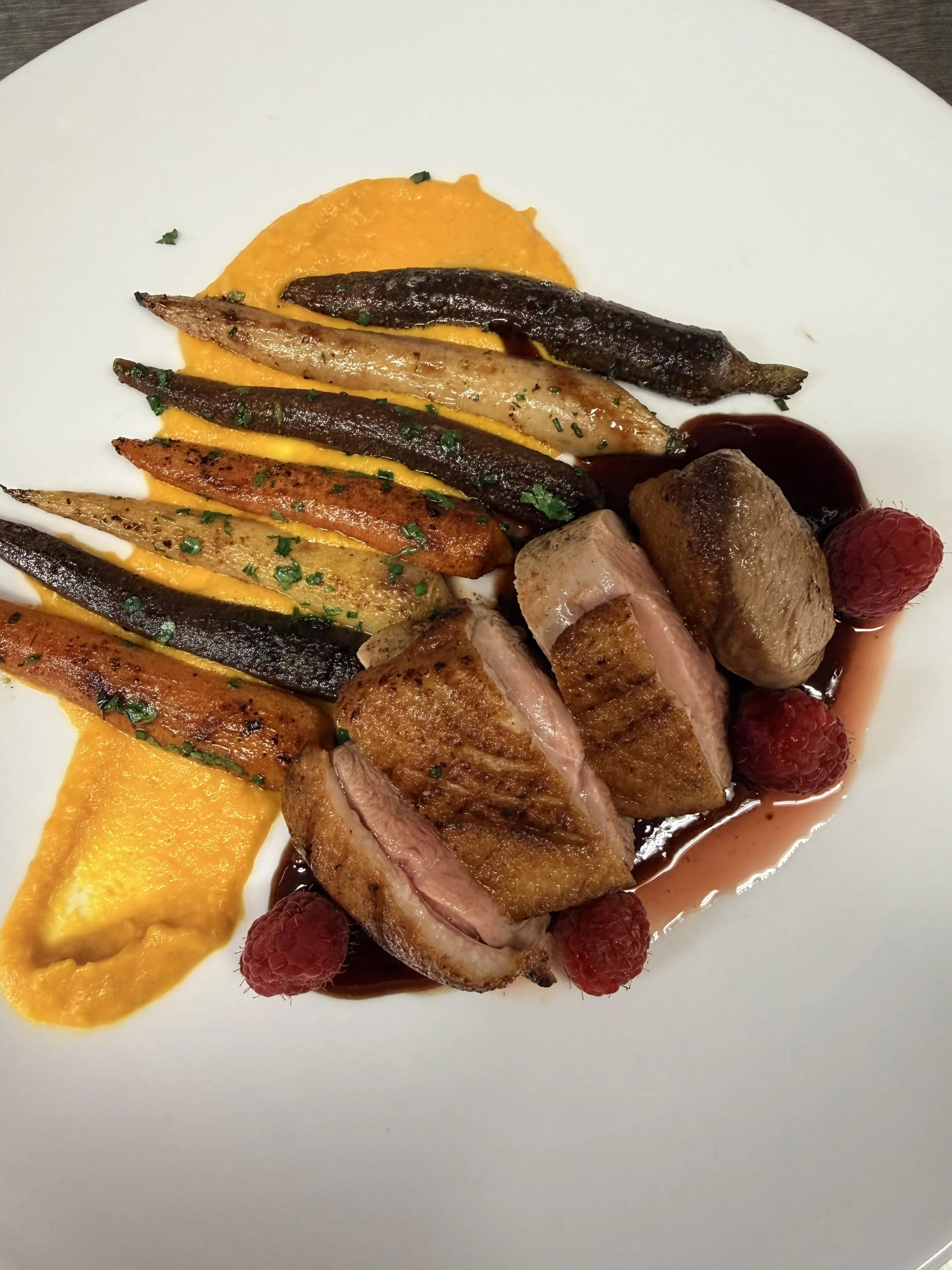 Seared Duck Breast, with roasted honey glazed carrots and a sweet potato puree, finished with a berry jus.