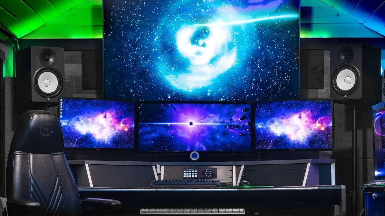 swashin's computer setup with three monitors, two large speakers, a gaming chair, and a keyboard in a room with green and blue lighting and space-themed digital artwork on the screens.