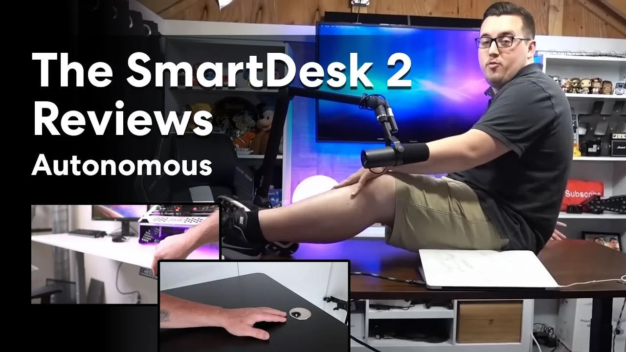 Thumbnail image of Matt Philie sitting at a desk with a large monitor, microphone, and computer setup, holding his legs with a review title overlay reading 'The SmartDesk 2 Reviews Autonomous'.