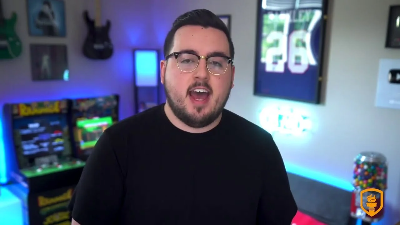 Matt Philie speaking in a room with arcade machines, a television, and colorful lighting.