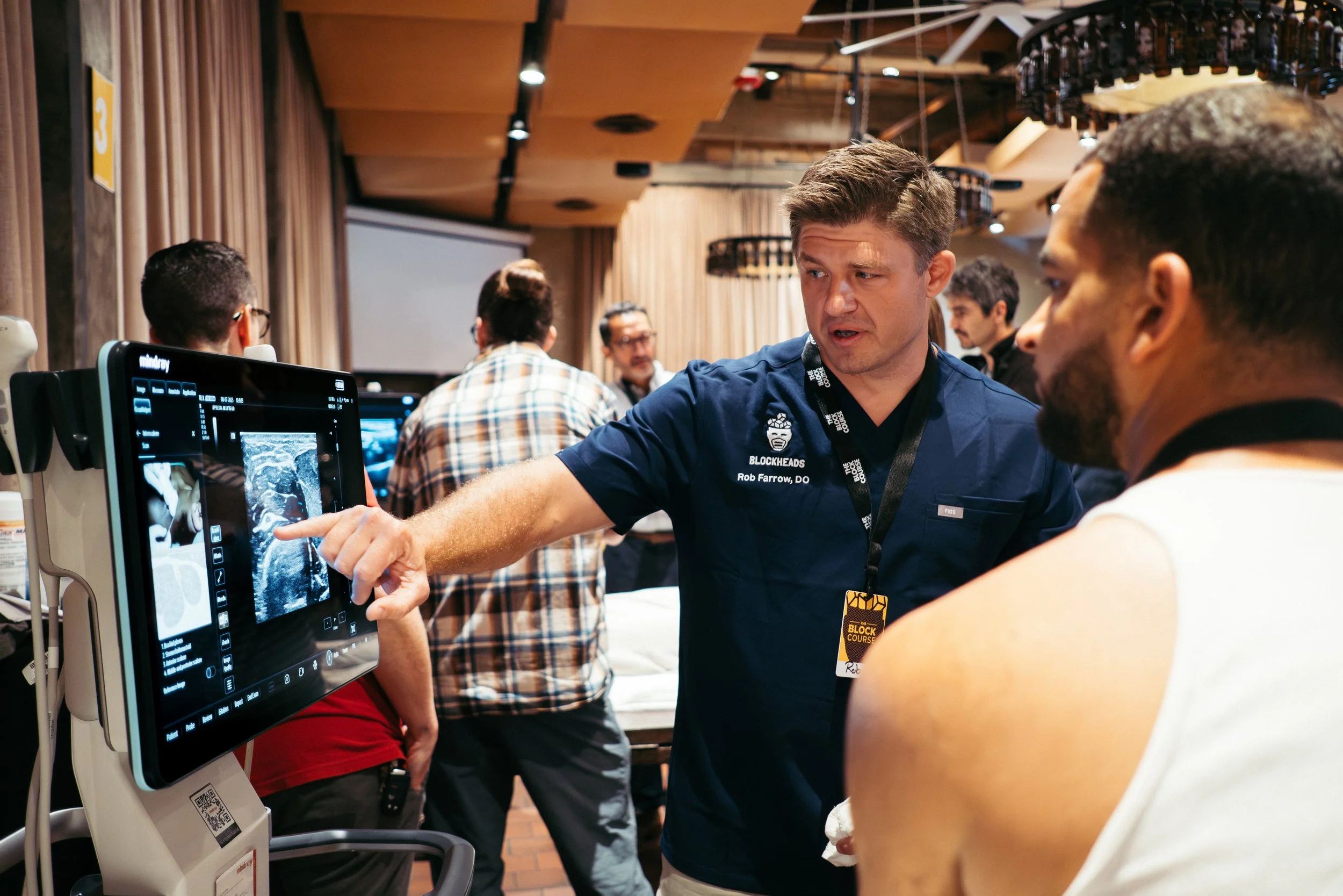 Medical professional showing an ultrasound scan on a monitor to an individual at a conference or workshop.