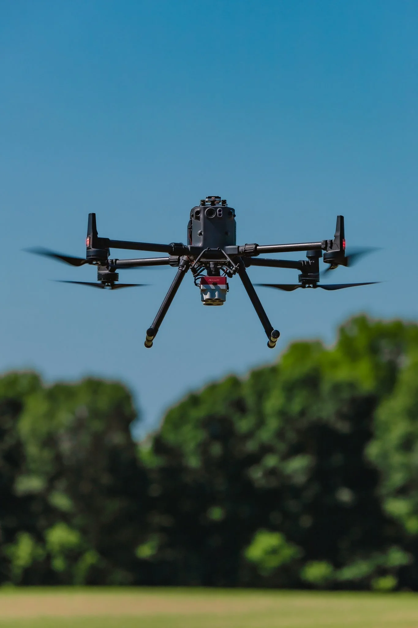DJI M300 flying over a farmer's corn field against a blue sky with trees in the background.