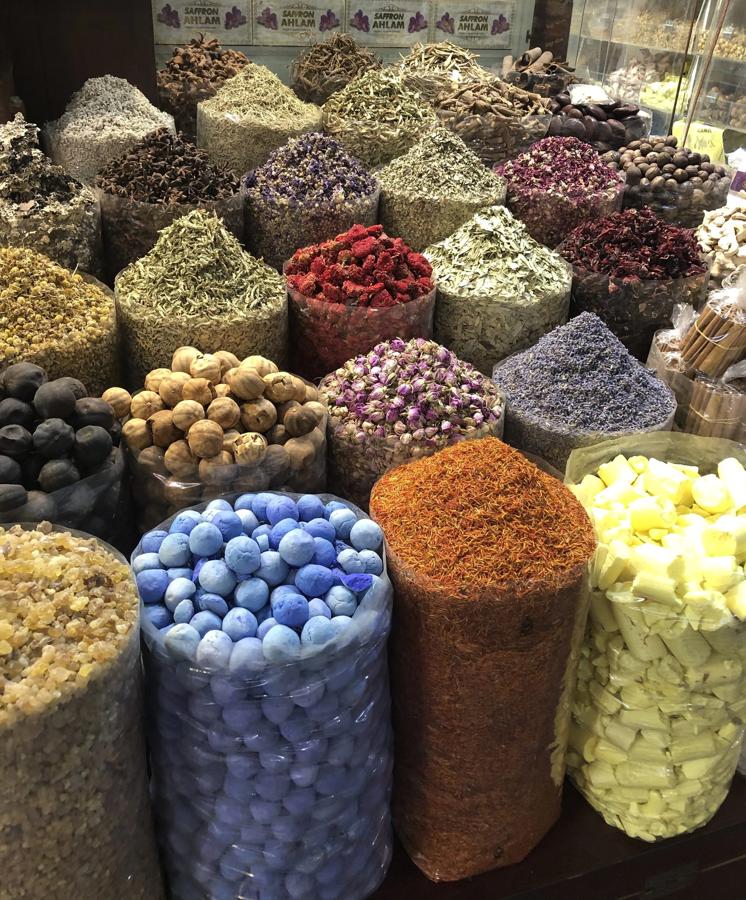 Various colorful spices and herbs displayed in bags at a market.