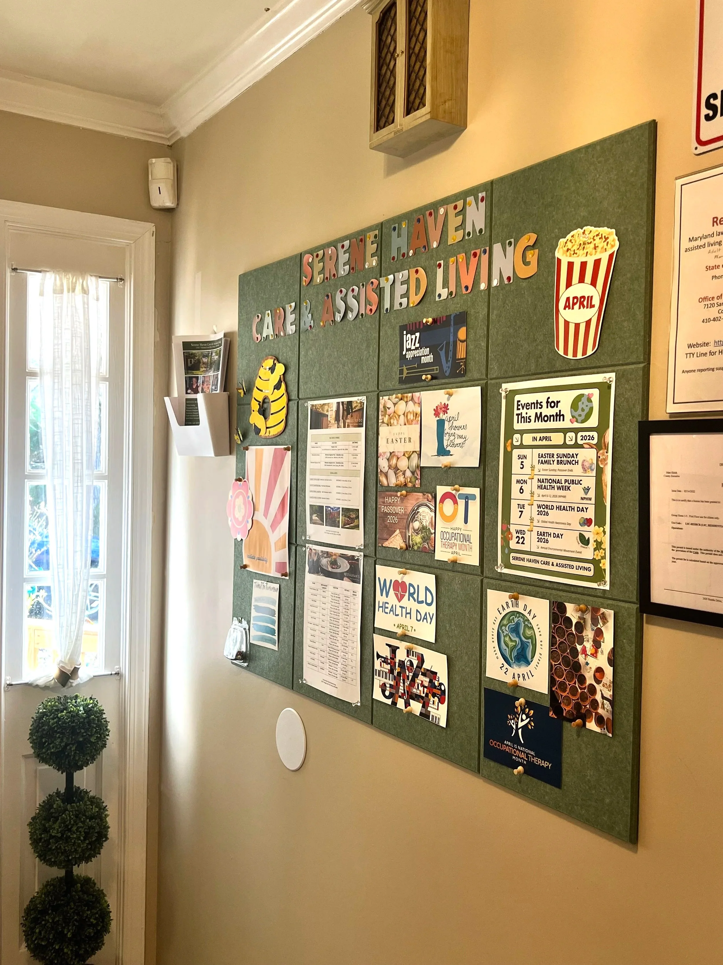 Indoor hallway with beige walls, white doors, framed pictures, ceiling lights, and wooden flooring.