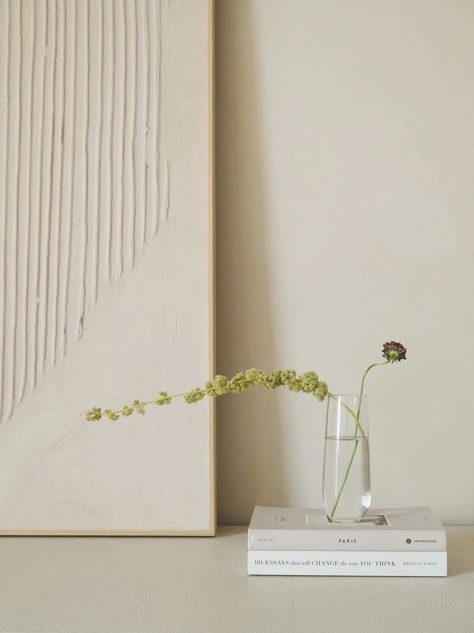 // STILL LIFE - sometimes it's the smallest moments that make a room - one stem, a stack of books, textured art in the background - captured is a vignette in our downtown brooklyn penthouse primary bedroom that has us slowing down - interior design &