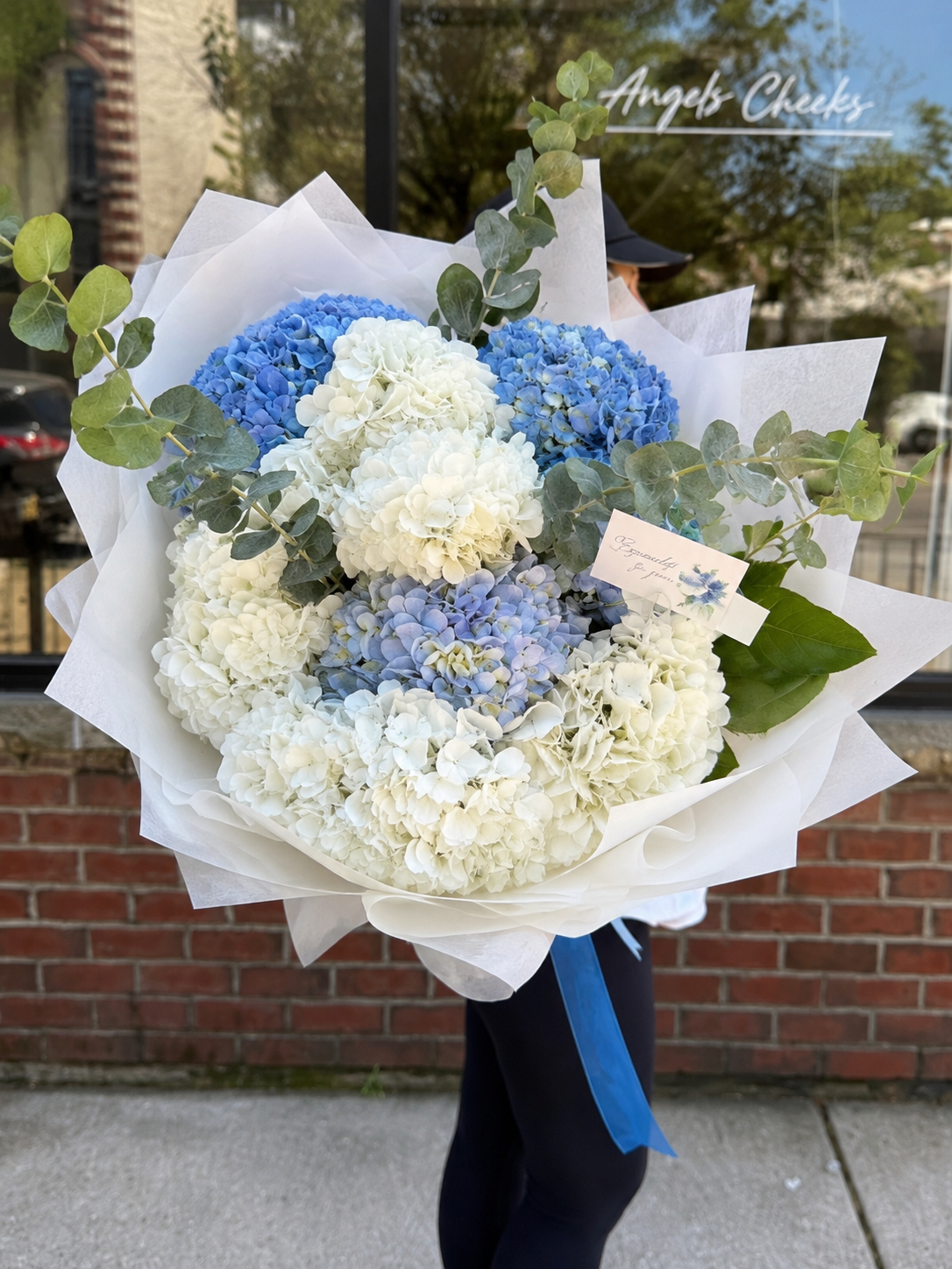 Large blue and white hydrangea bouquet with eucalyptus outside Angels Cheeks Florist in Roscoe Village, Chicago