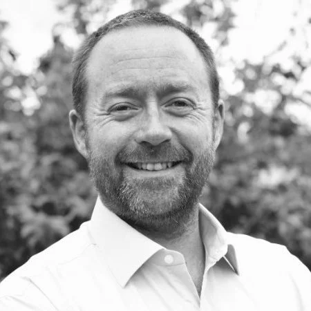 Smiling man outdoors with trees in background, black and white photo
