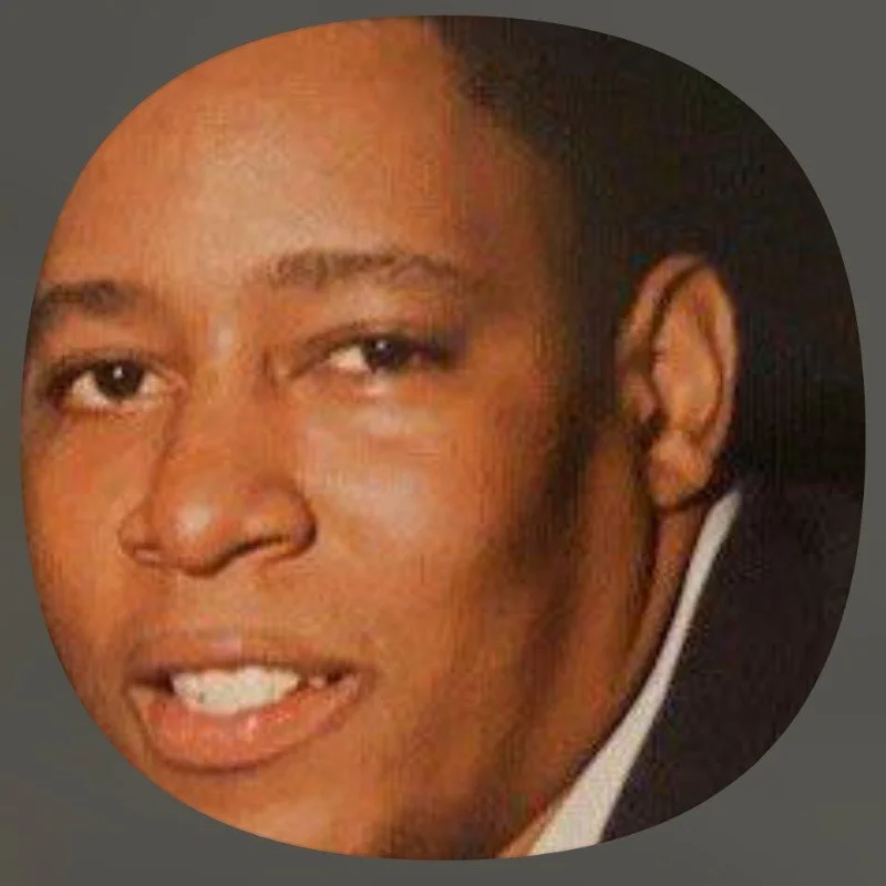 Close-up of a smiling person in a dark background.