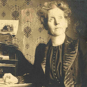 A woman in formal clothes sitting at a desk.