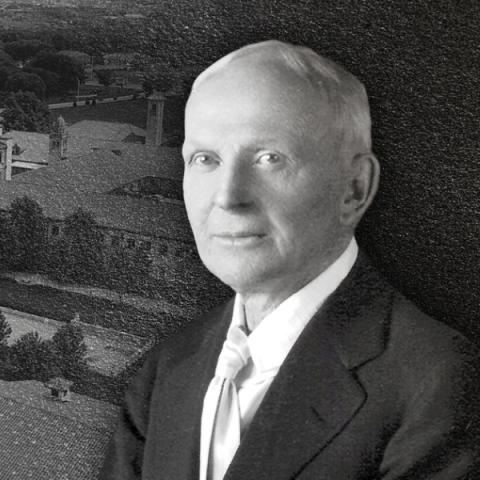 A man in suit and tie in front of a picture of Unity Village.