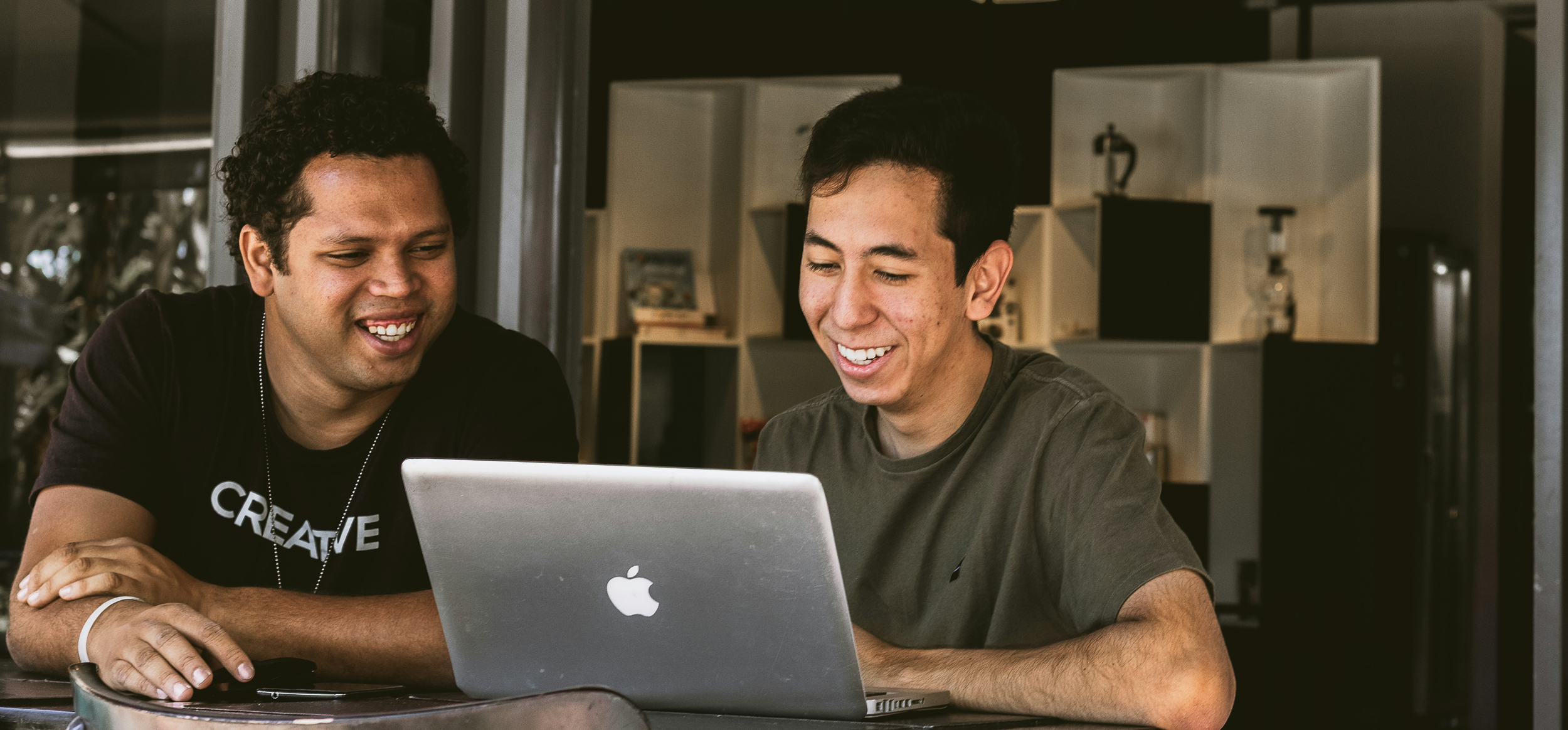 Two men sitting in front of a laptop
