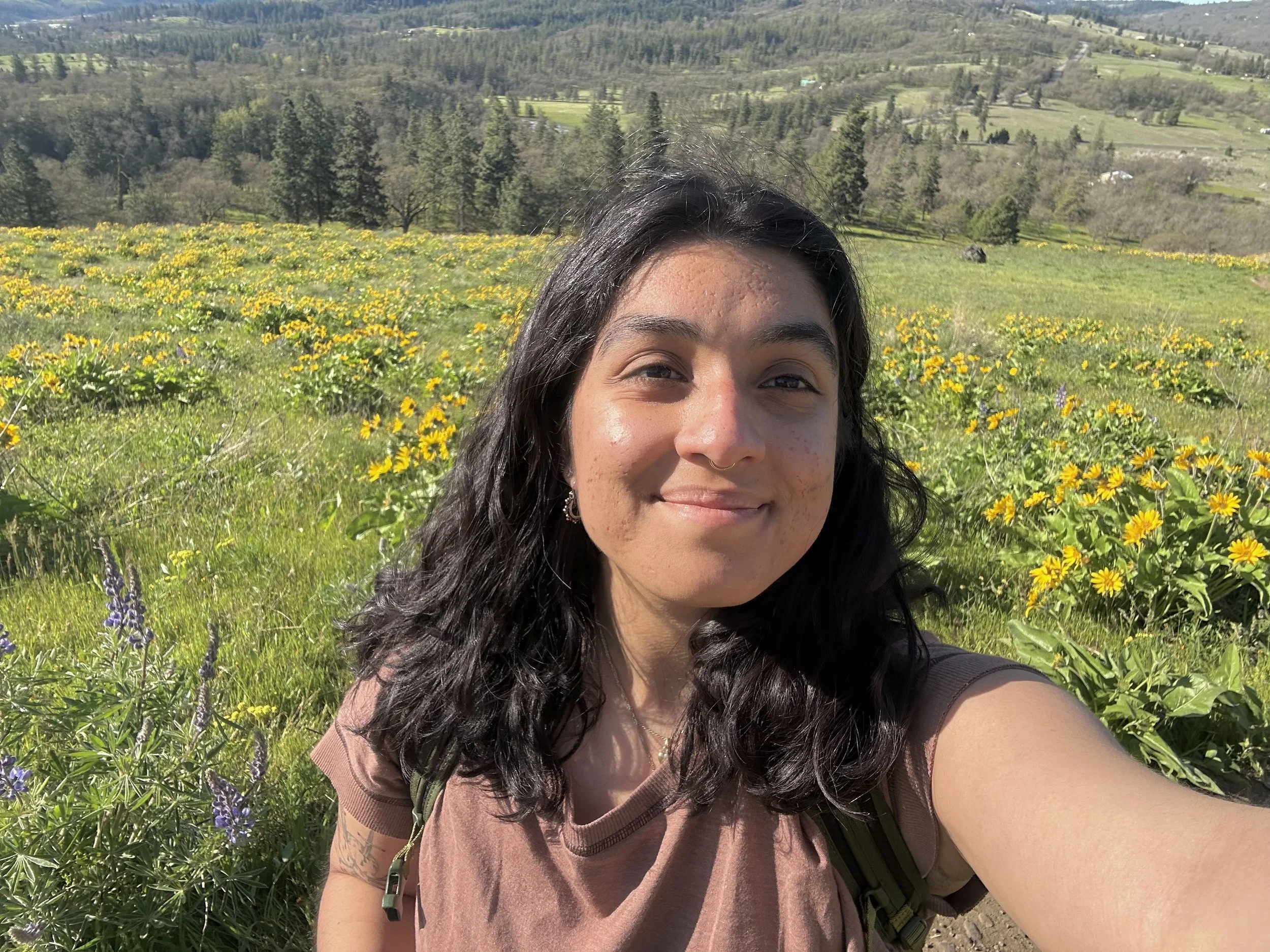 A picture of Valeria Zanzano, the kindergarten assistant teacher at Portland Forest School.  The picture is a selfie with a meadow in the background.