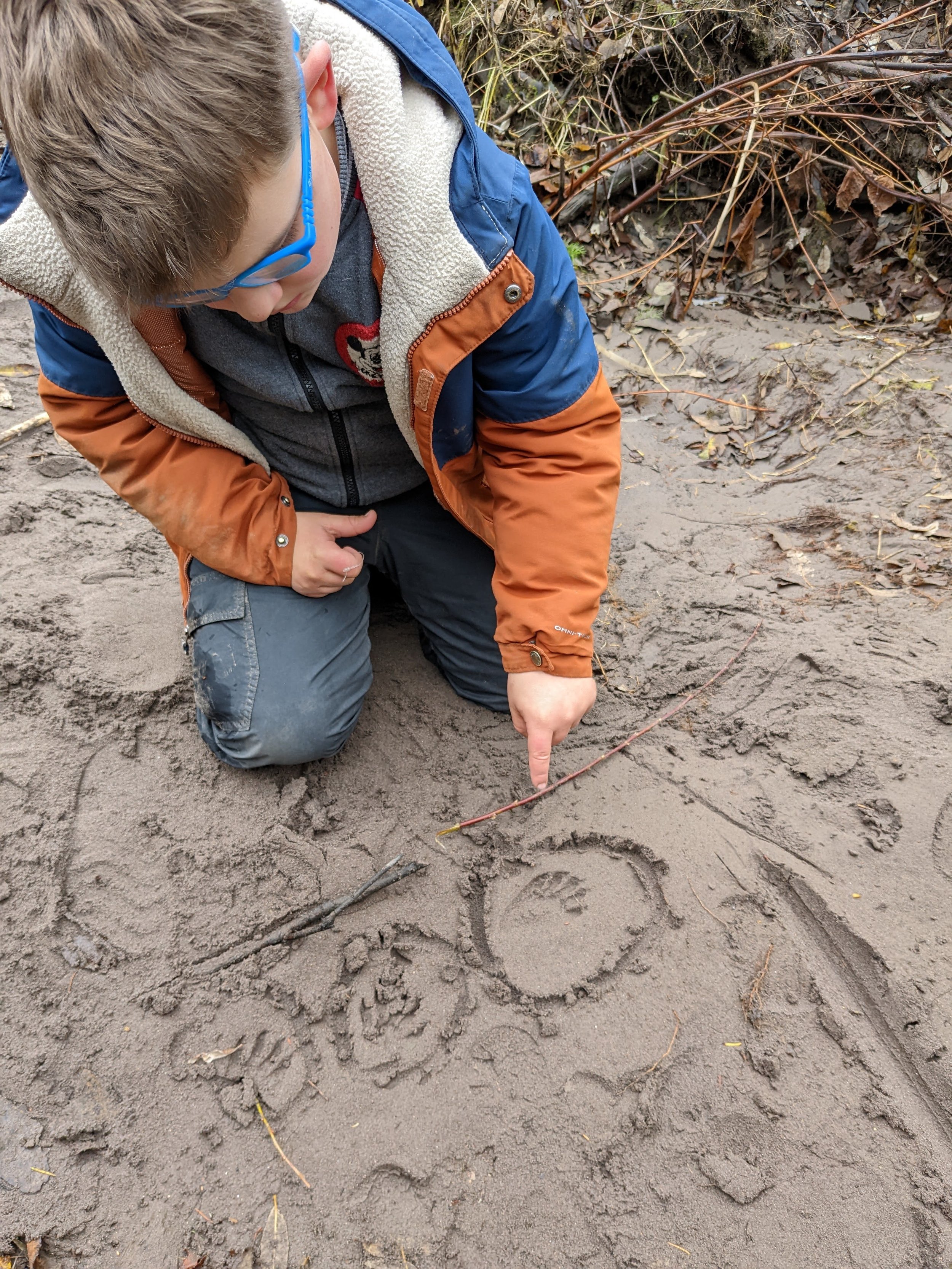Forest school elementary student drawing in sand at the nonprofit, private school, alternative school, nontraditional school in Portland, OR with community based, multiage education, low ratios and open enrollment
