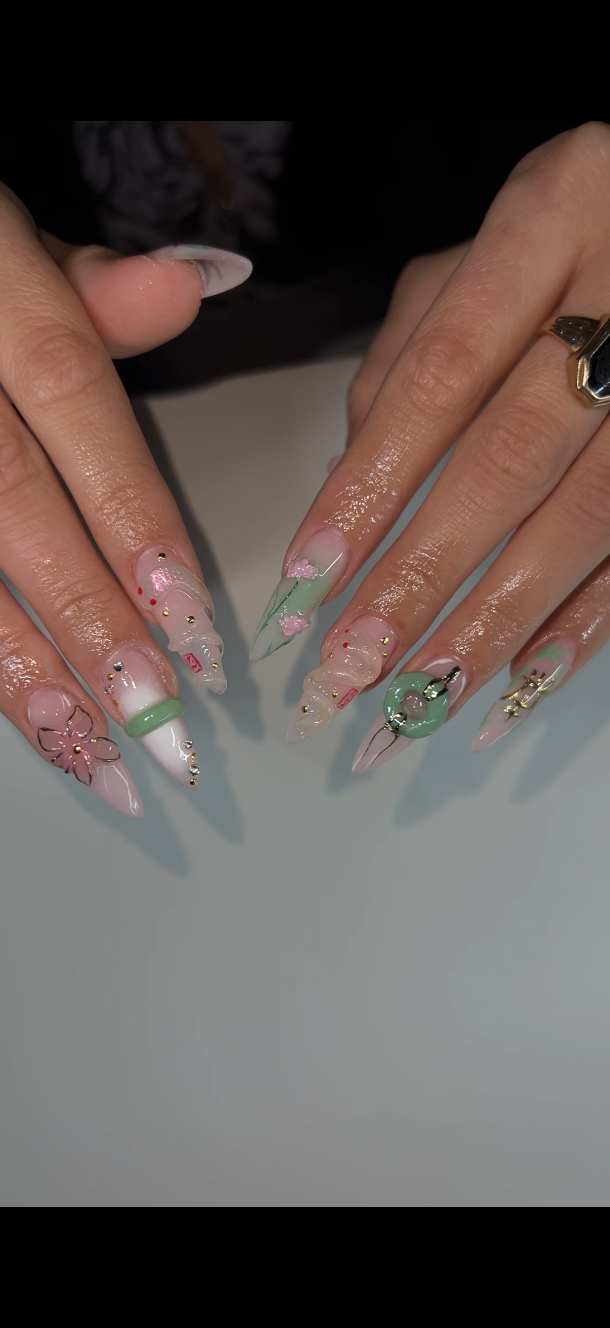 Detailed long nail extensions with green, white and gold chrome accents.