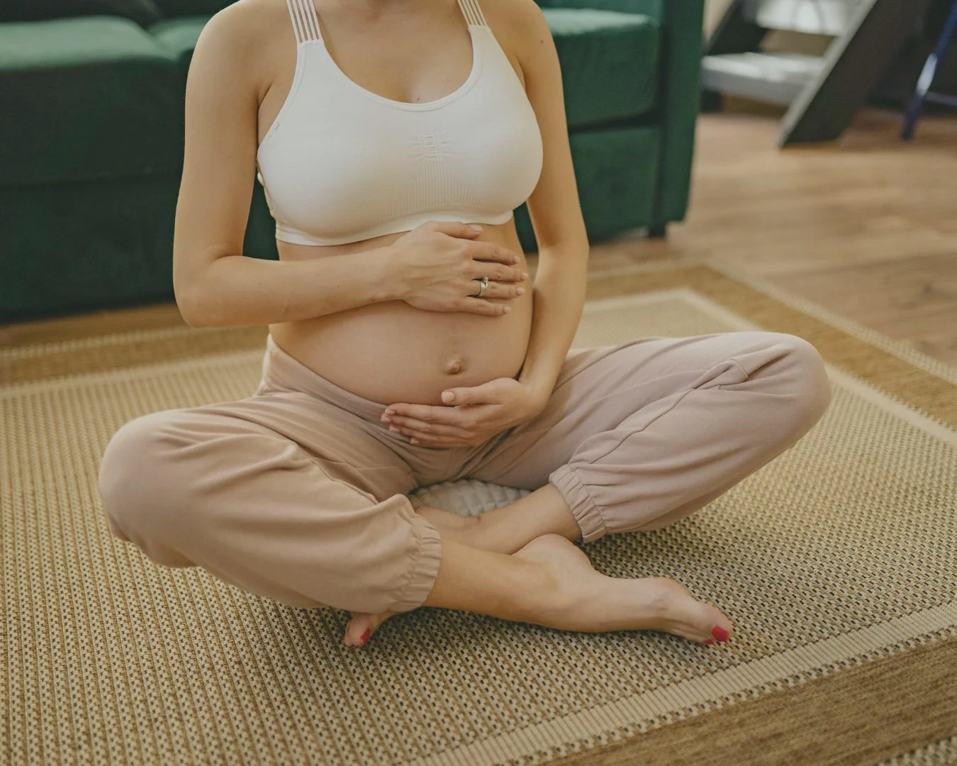 Pregnant woman doing yoga, gently holding her belly