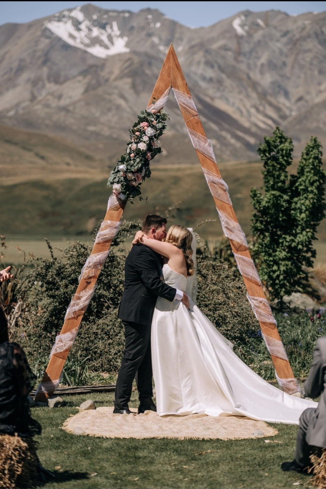 ashburton lakes wedding ceremony under triangular arch decorated with faux flowers