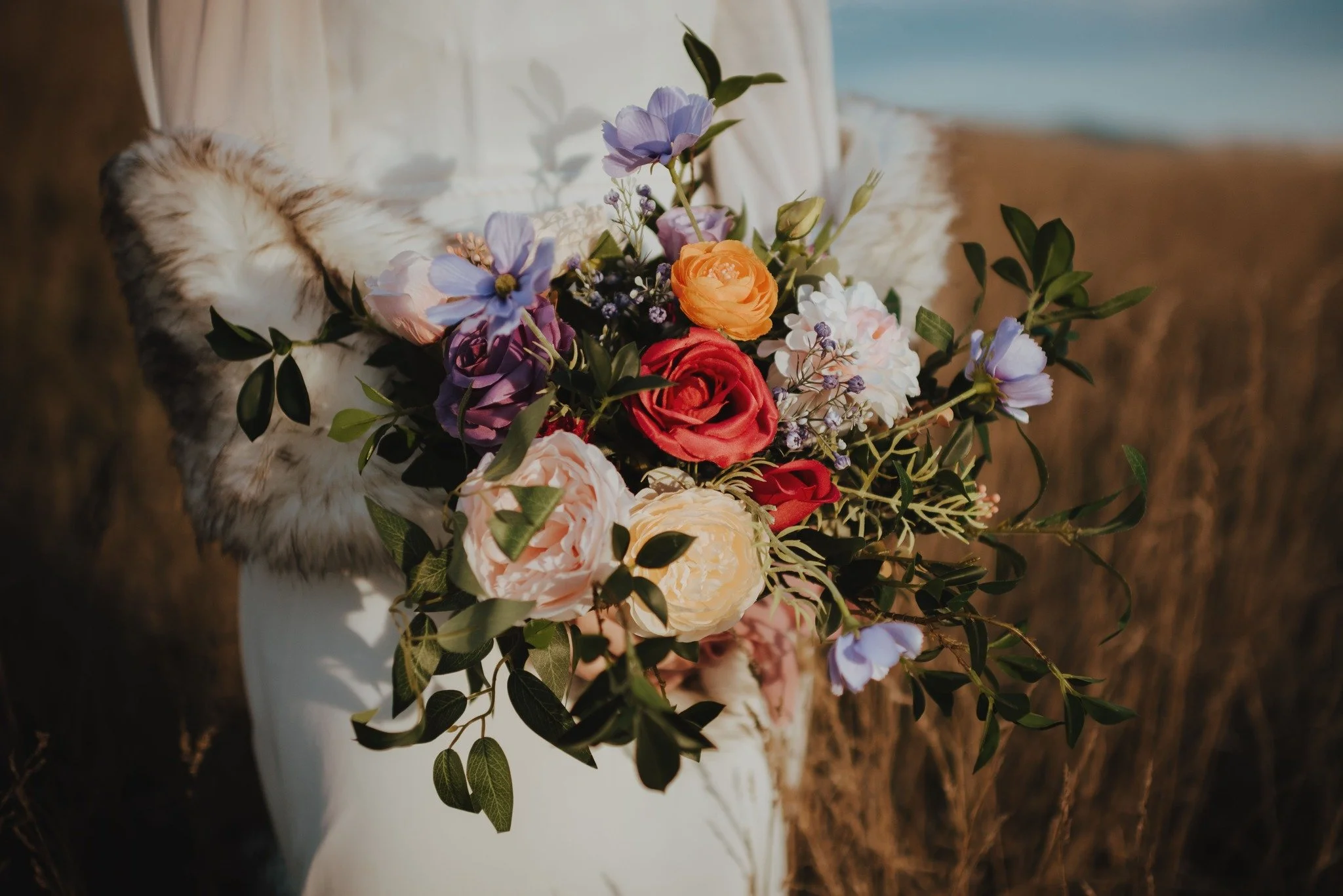 spring inspired wedding bouquet with oranges, purples and cream tones