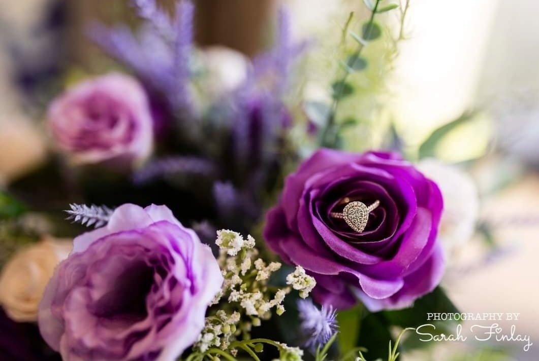 wedding ring detail photograph with purple artificial flowers