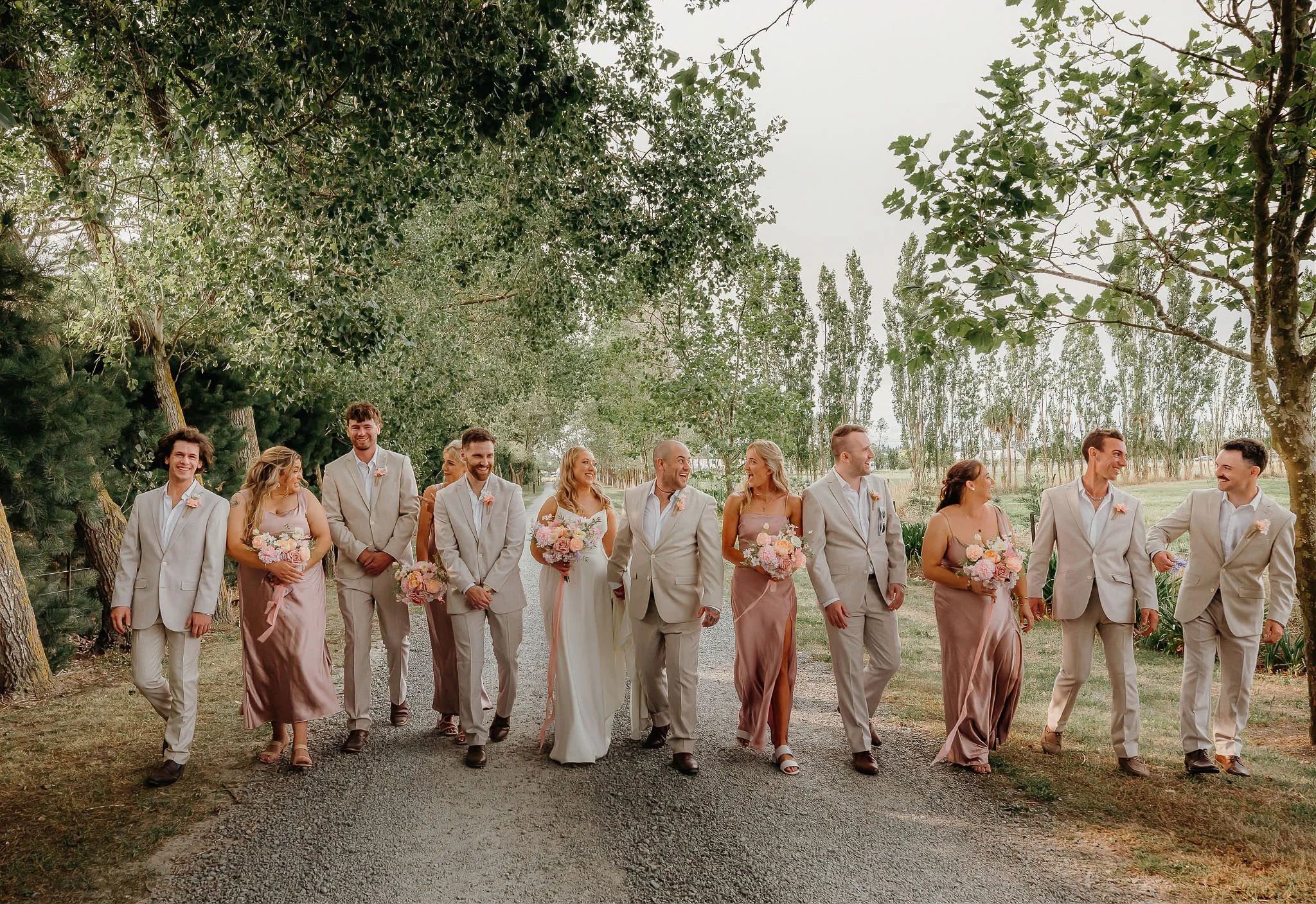 Bridal party walking together chatting and smiling laughing holding bouquets