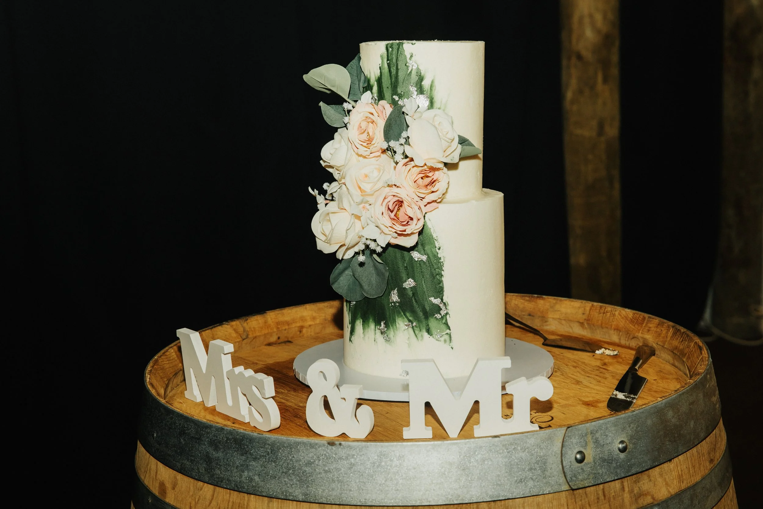 new zealand wedding florist decorates cake in pink peonies