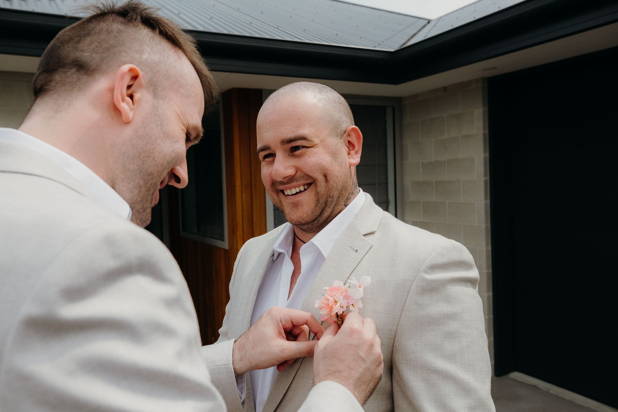 best man pinning boutonnière to the grooms suit 