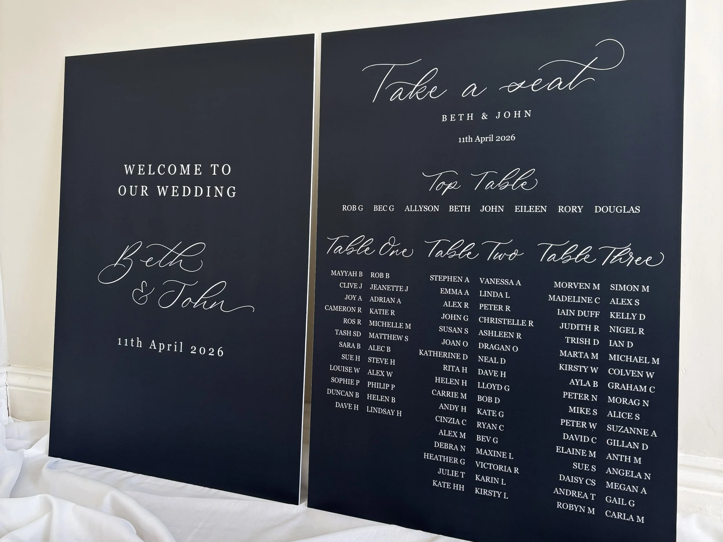 A1 foamex wedding signs sitting side by side. The A1 board on the left is wedding welcome sign, and the A1 board on the right is a wedding seating plan. Finished with digitised modern calligraphy and a complimentary font. 