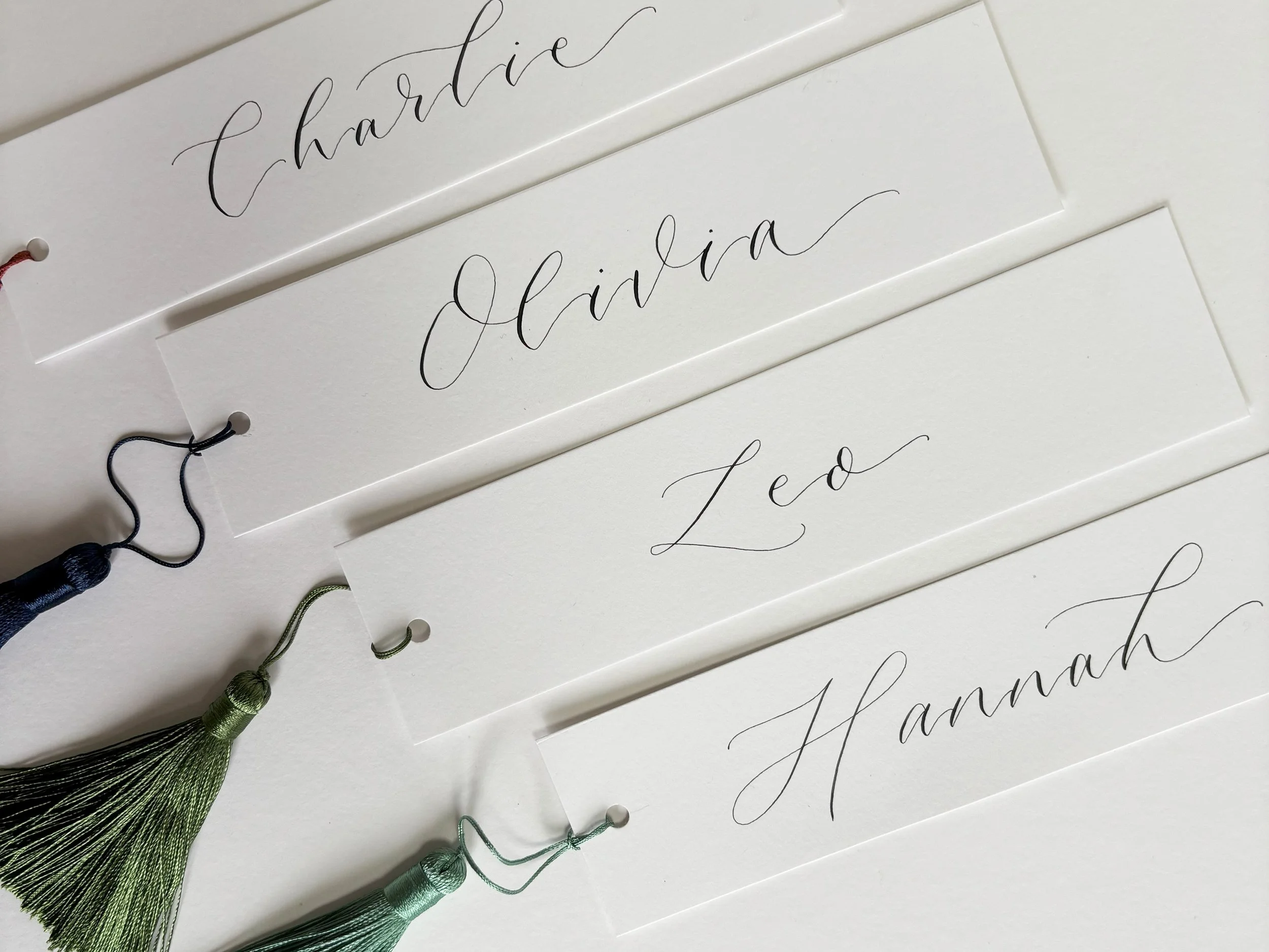 White personalised bookmarks finished with handwritten modern calligraphy and a silk tassel