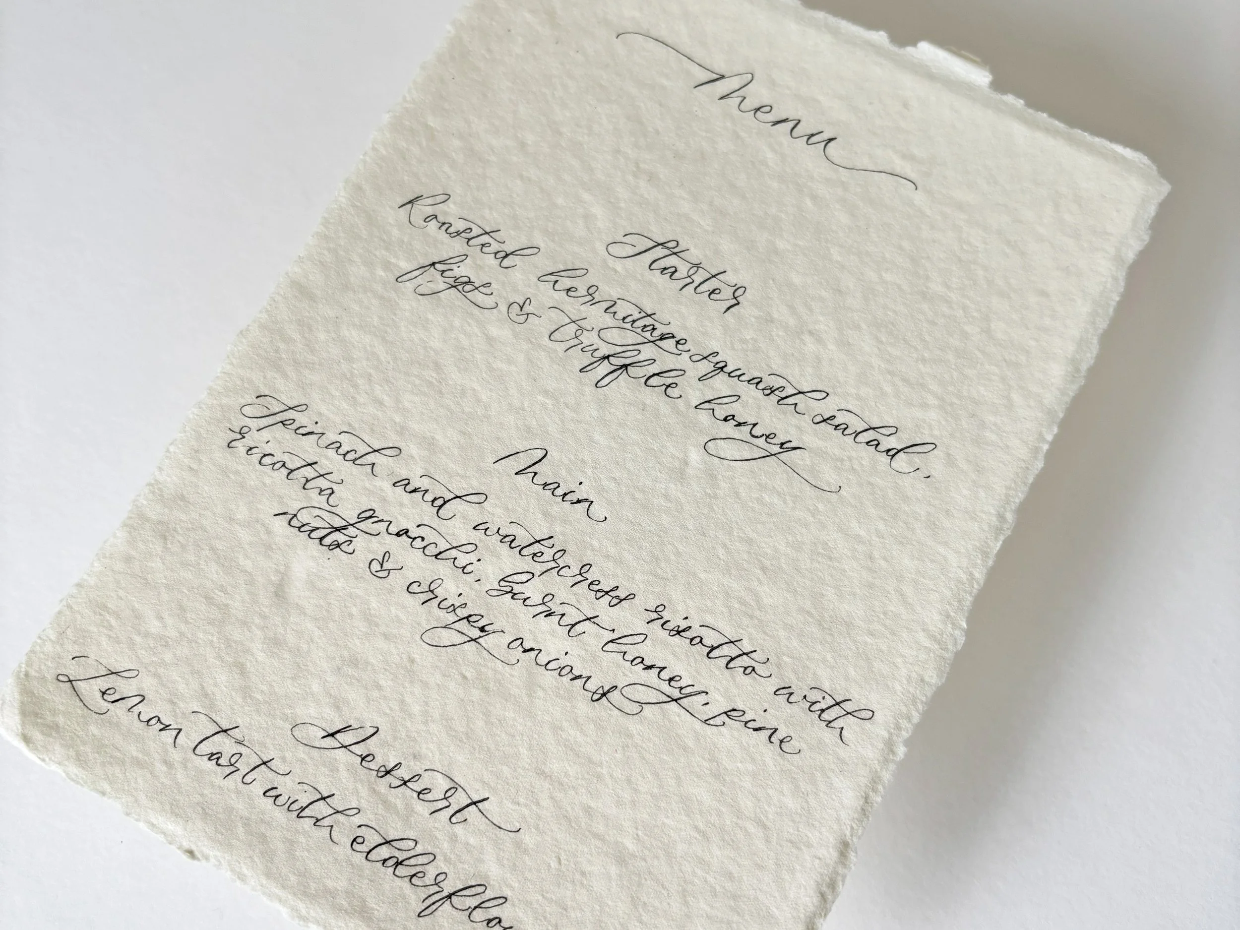 A5 ivory deckled edge wedding menu. Written in modern calligraphy using a traditional nib and ink. Personalised handwritten wedding menu. 