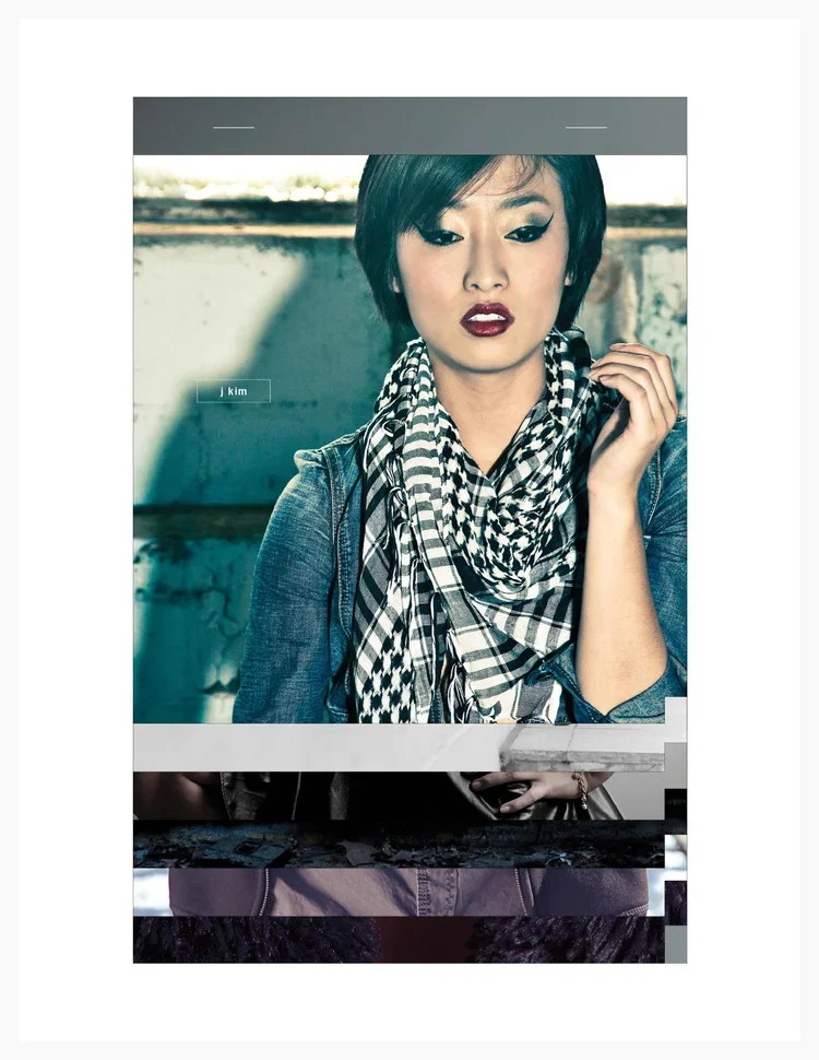 A woman with short black hair and bold makeup, wearing a denim jacket and black-and-white patterned scarf, looking downward with her hand near her face, standing outdoors in front of a weathered wall.