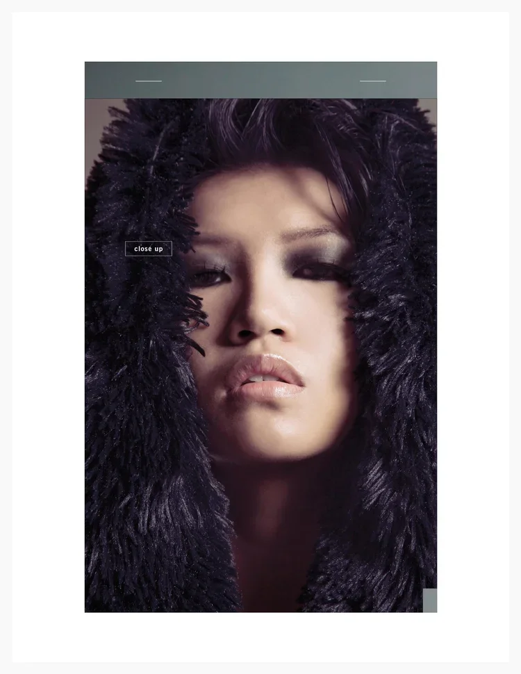 Close-up of a woman with dark hair and smoky eye makeup, wearing a large black fur hood.