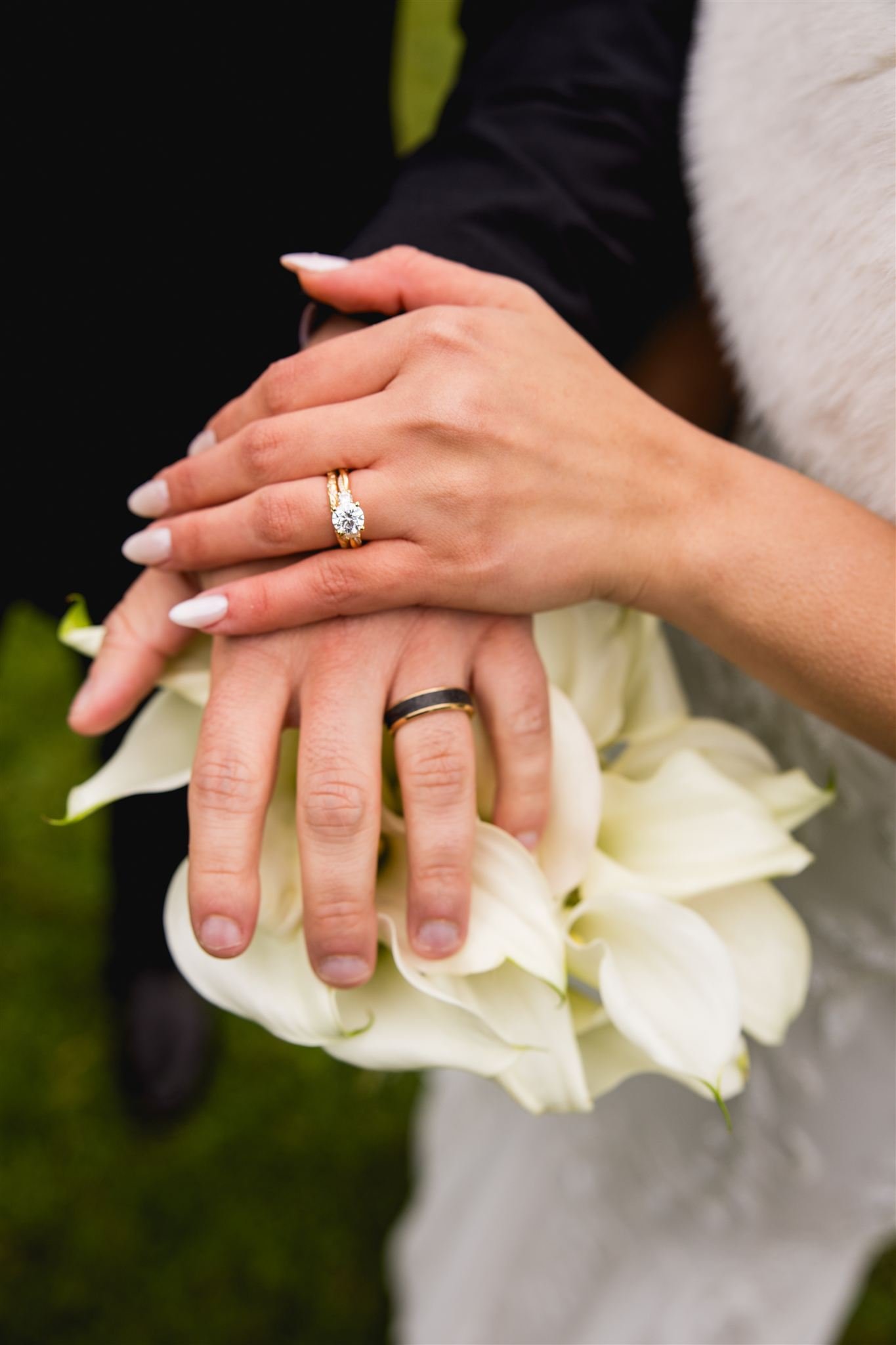 bride and groom showing off their wedding ring bands on top of a white floral bouquet at their micro wedding in Boston