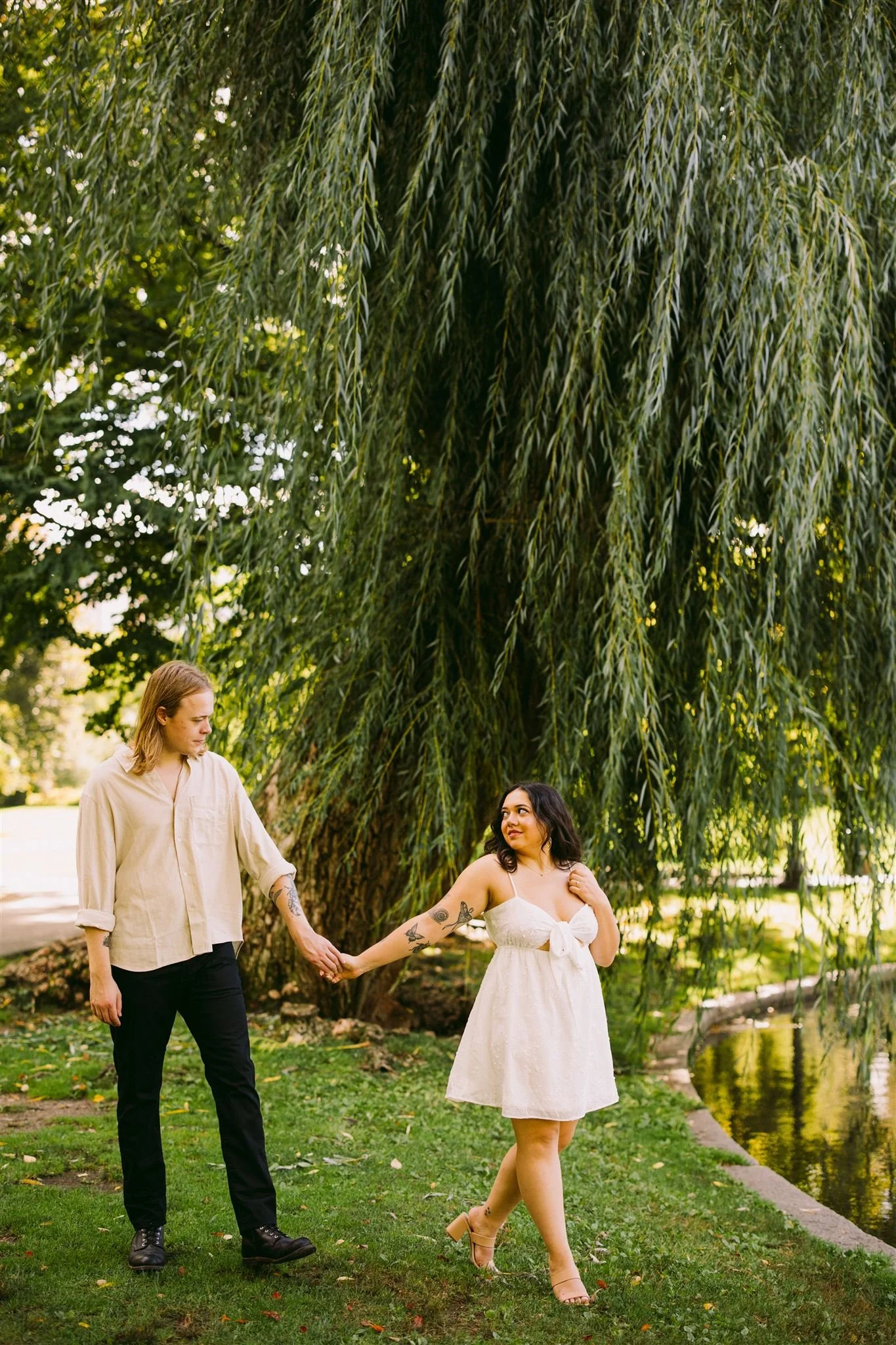 Couple walking under a weeping willow tree during a Boston Public Garden engagement photo session.