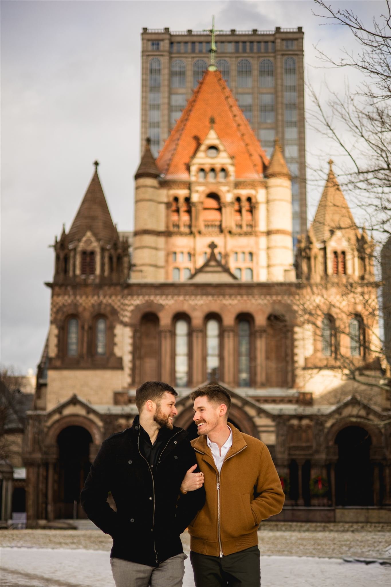 Engaged couple walking in front of Trinity Church in Copley Square, Boston