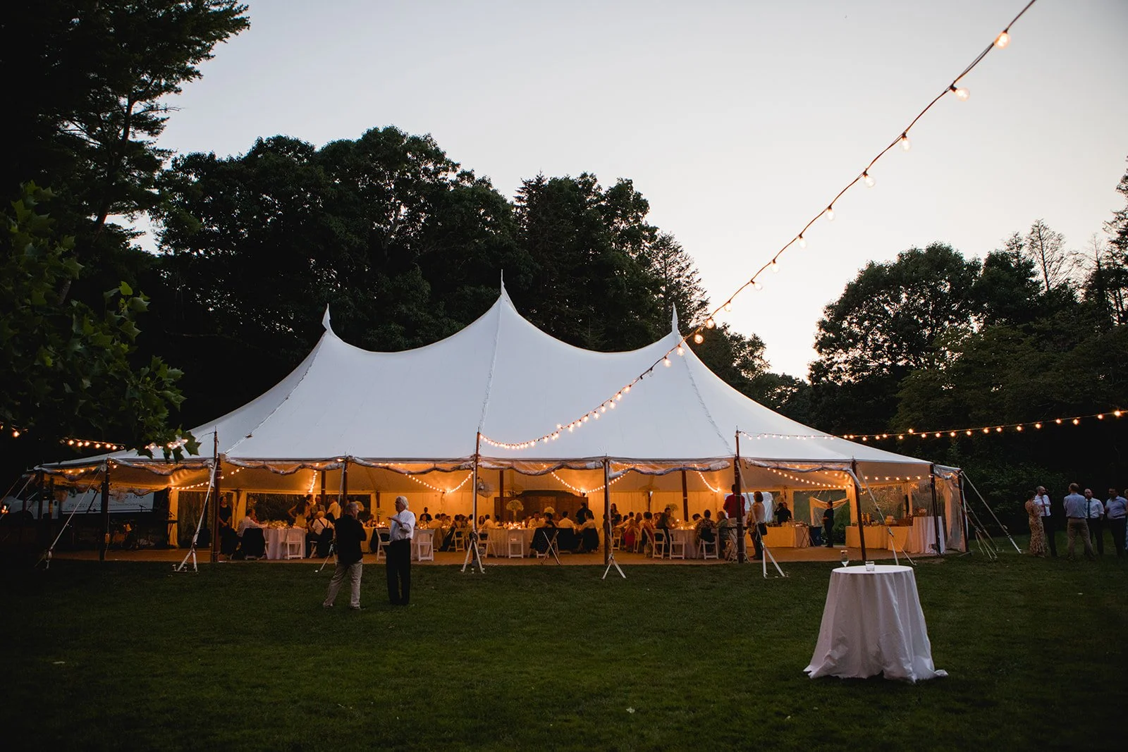 Outdoor wedding reception tent lit with string lights at night at Estate at Moraine Farm in Beverly, Massachusetts