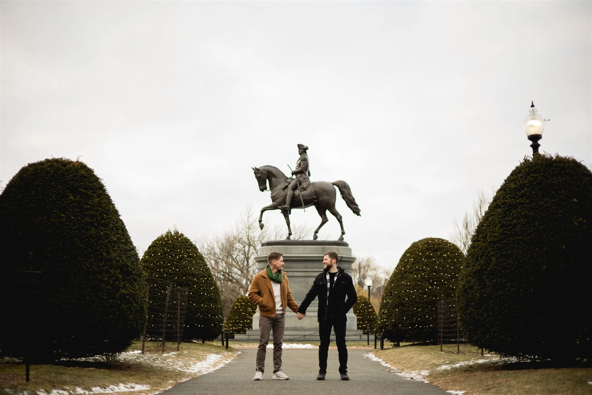 Engaged couple holding hands and smiling at each other in the Boston Public Garden in Boston
