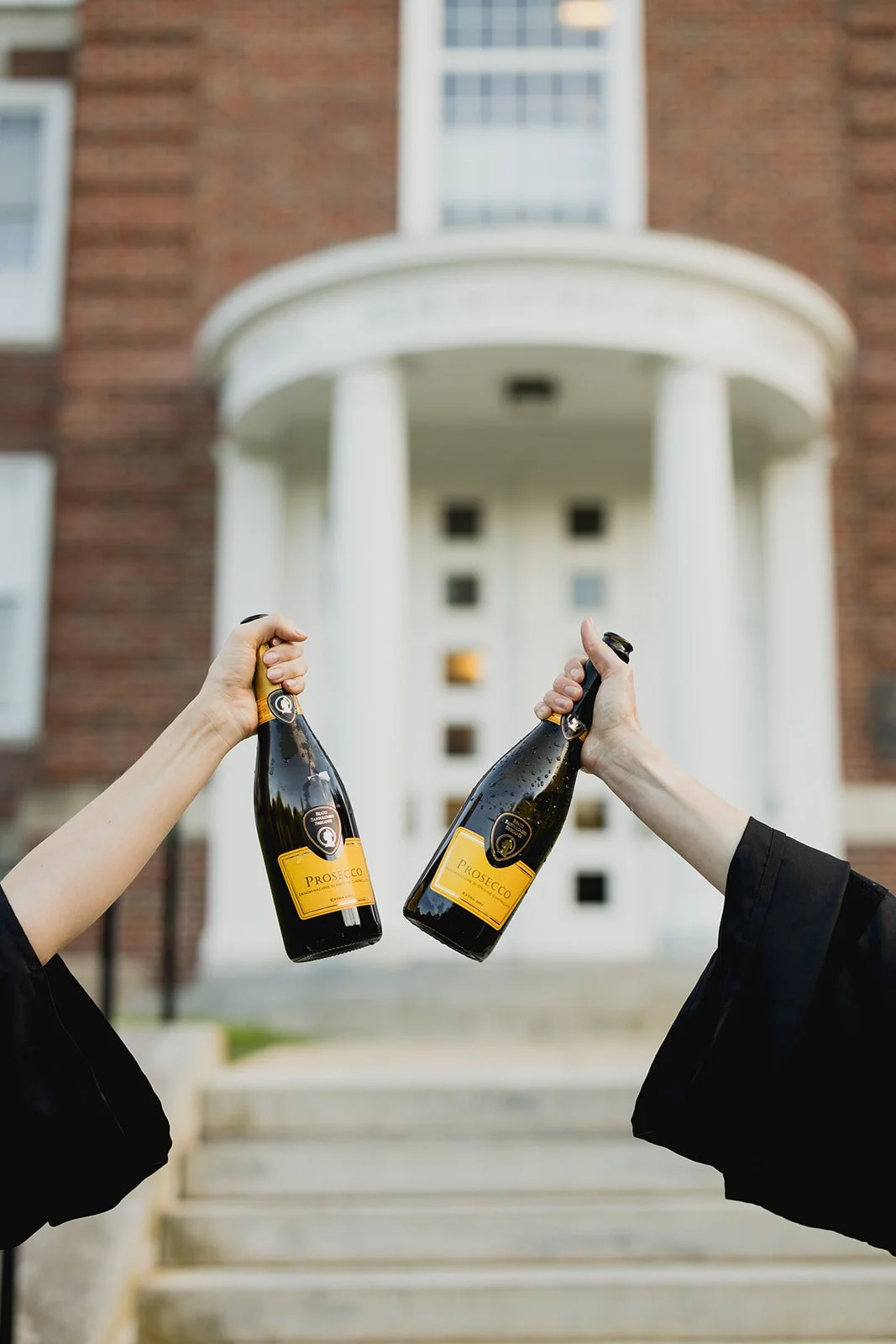 Boston College graduates celebrating their graduation with champagne in front of an iconic campus building
