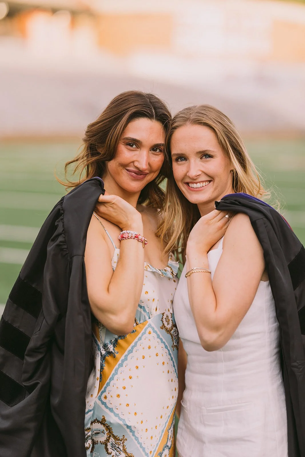 Boston College graduates posing and holding their graduation gowns on their shoulder