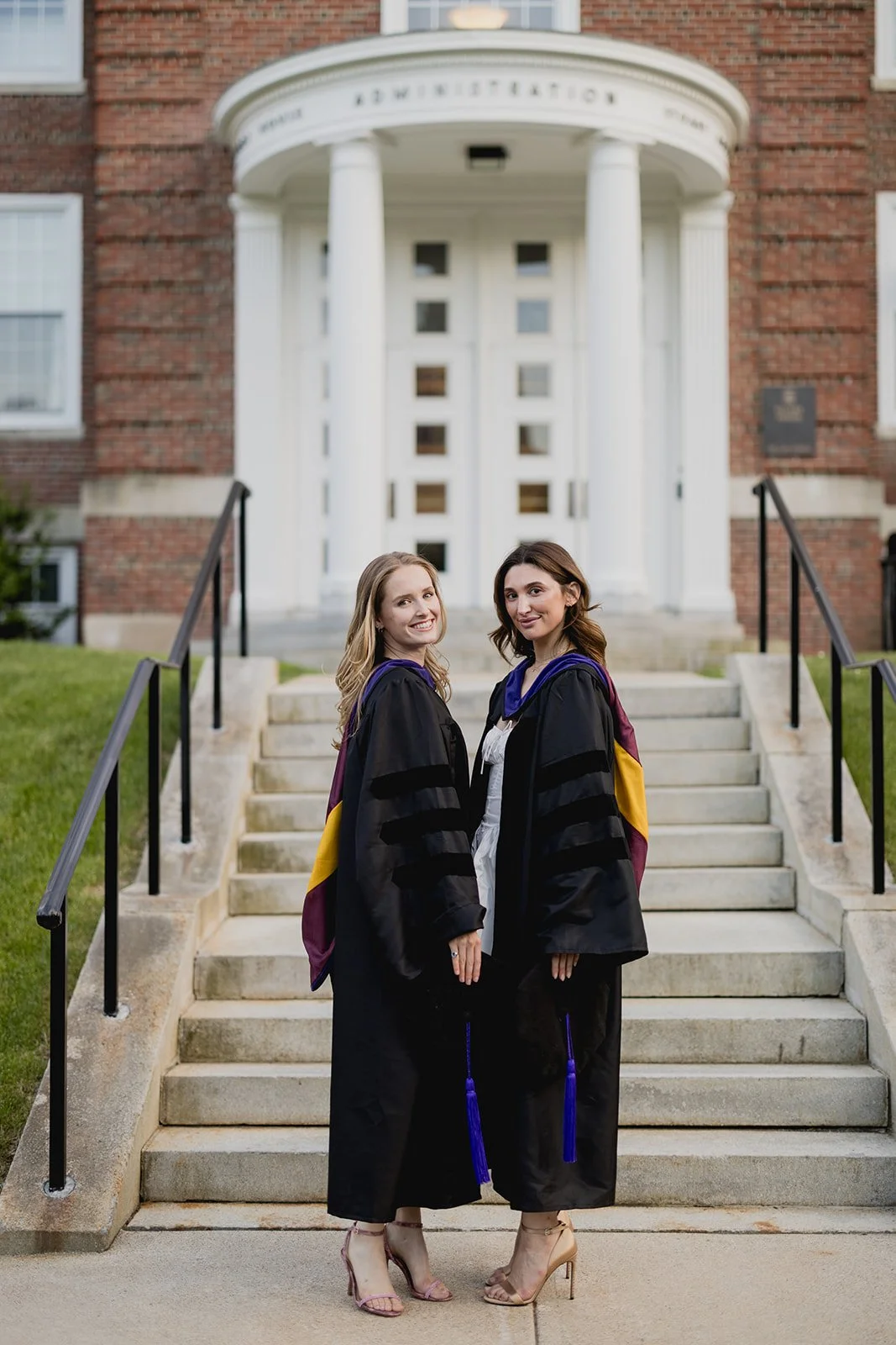 Boston College graduates proudly posing in front of iconic stairway at Boston College