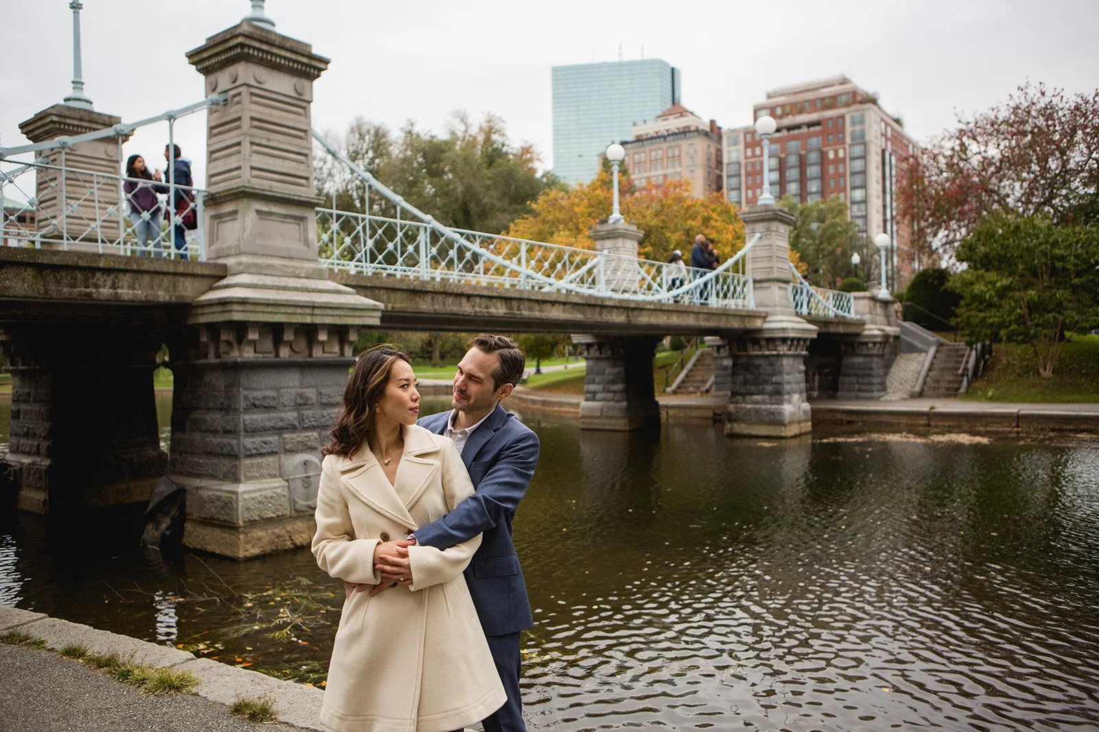Couple embracing near the iconic footbridge in the Boston Public Garden during a Boston engagement photo session.