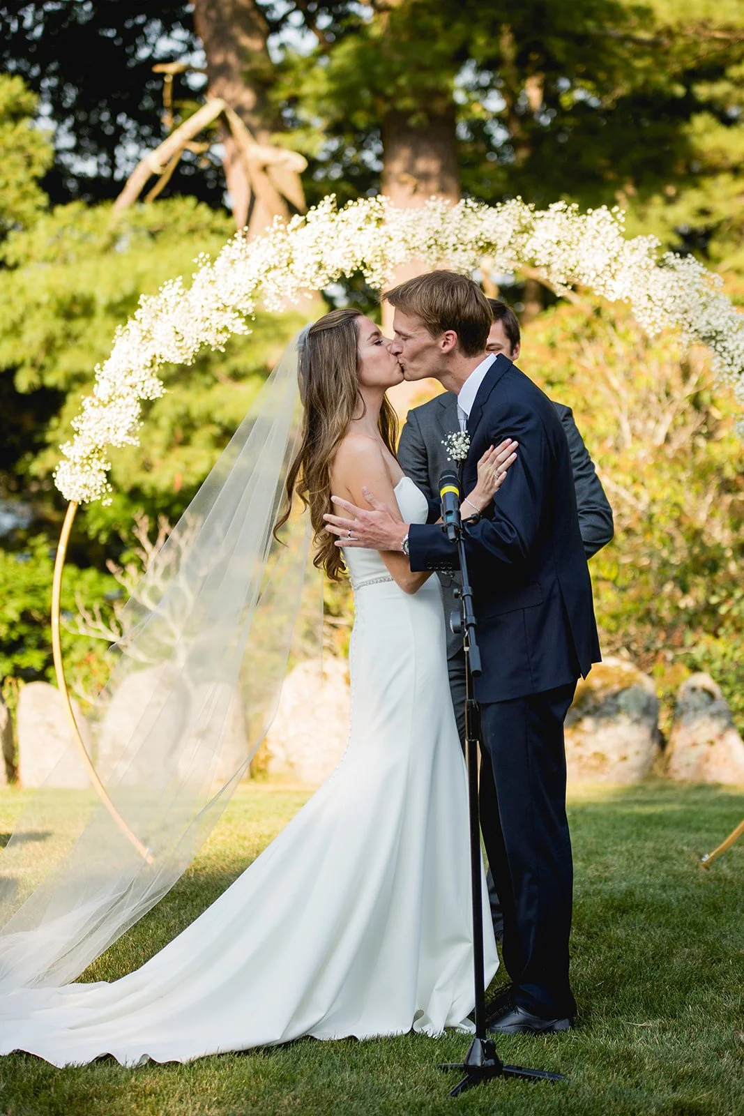 Bride and groom sharing their first kiss during outdoor wedding ceremony at Estate at Moraine Farm in Beverly, MA