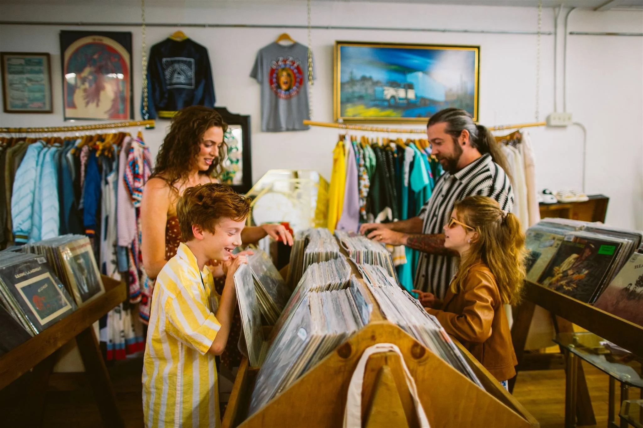 Cinematic family photography session in a record store in Bisbee, Arizona, capturing parents and children browsing vinyl together in a warm, storytelling-style portrait.
