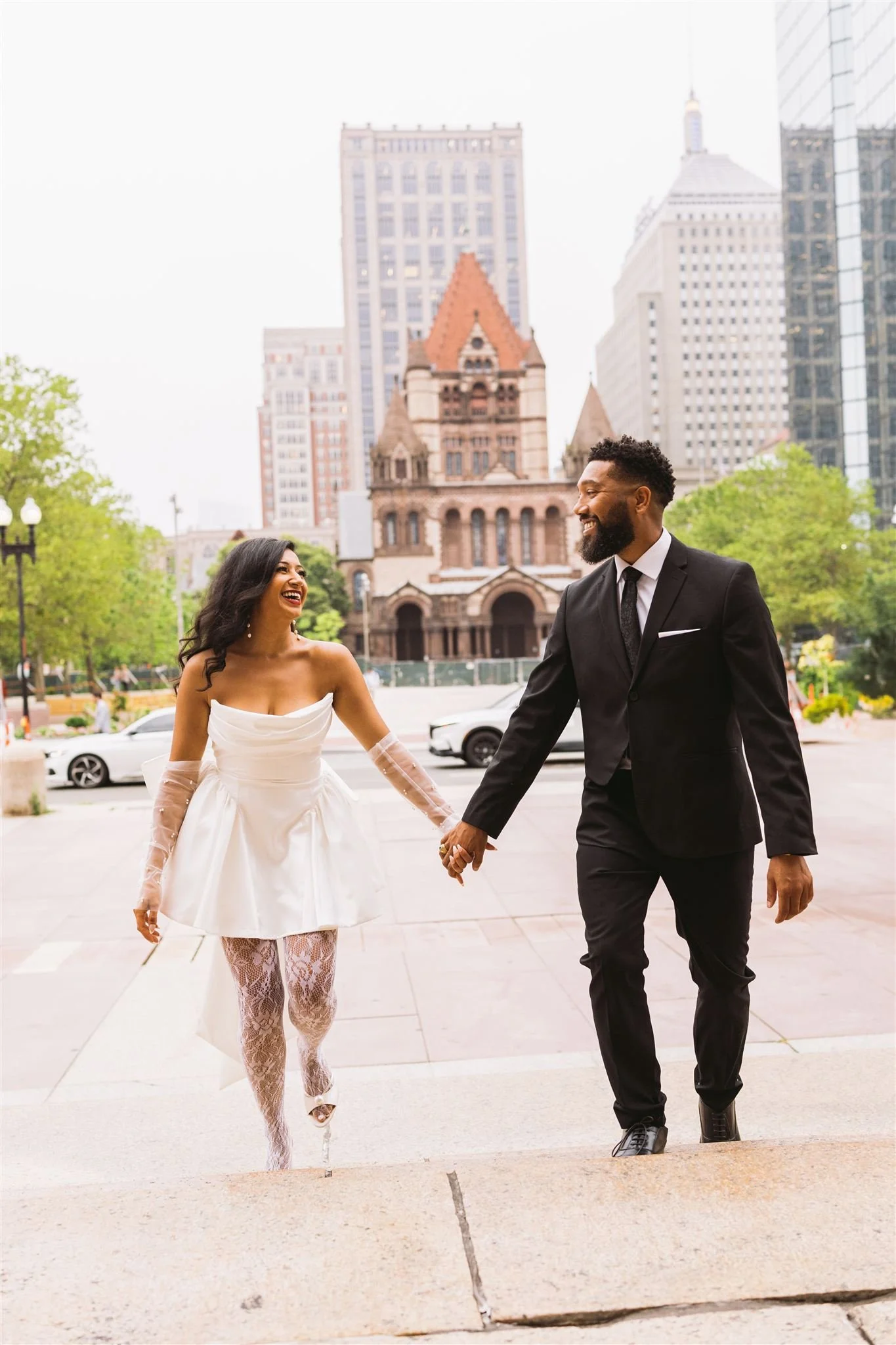 Newly engaged couple holding hands walking through Copley Square in Boston.