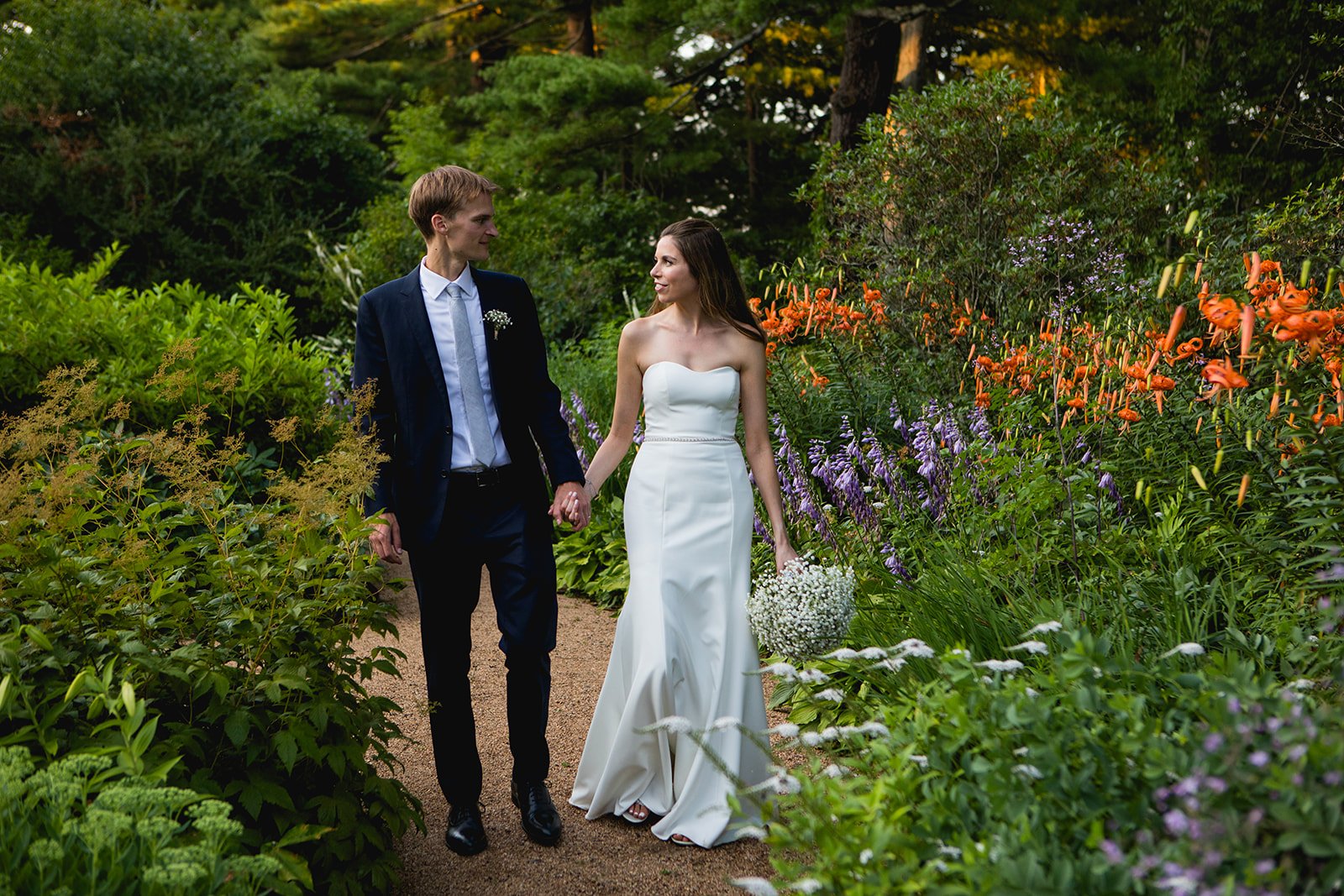 Bride and groom walking through garden path during portraits at Estate at Moraine Farm wedding in Beverly, Massachusetts