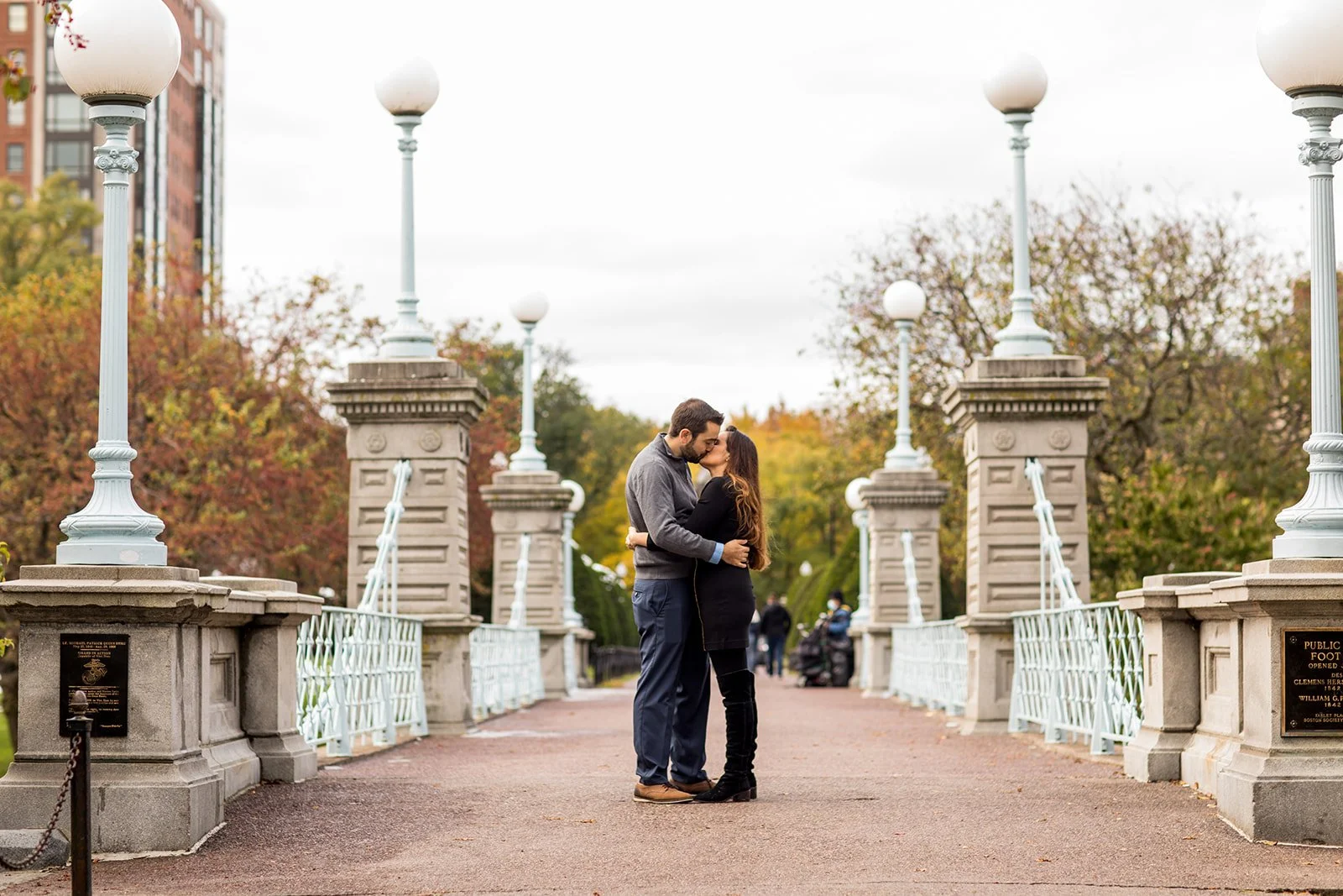 Couple standing together on the famous footbridge in the Boston Public Garden during a romantic engagement photo session.