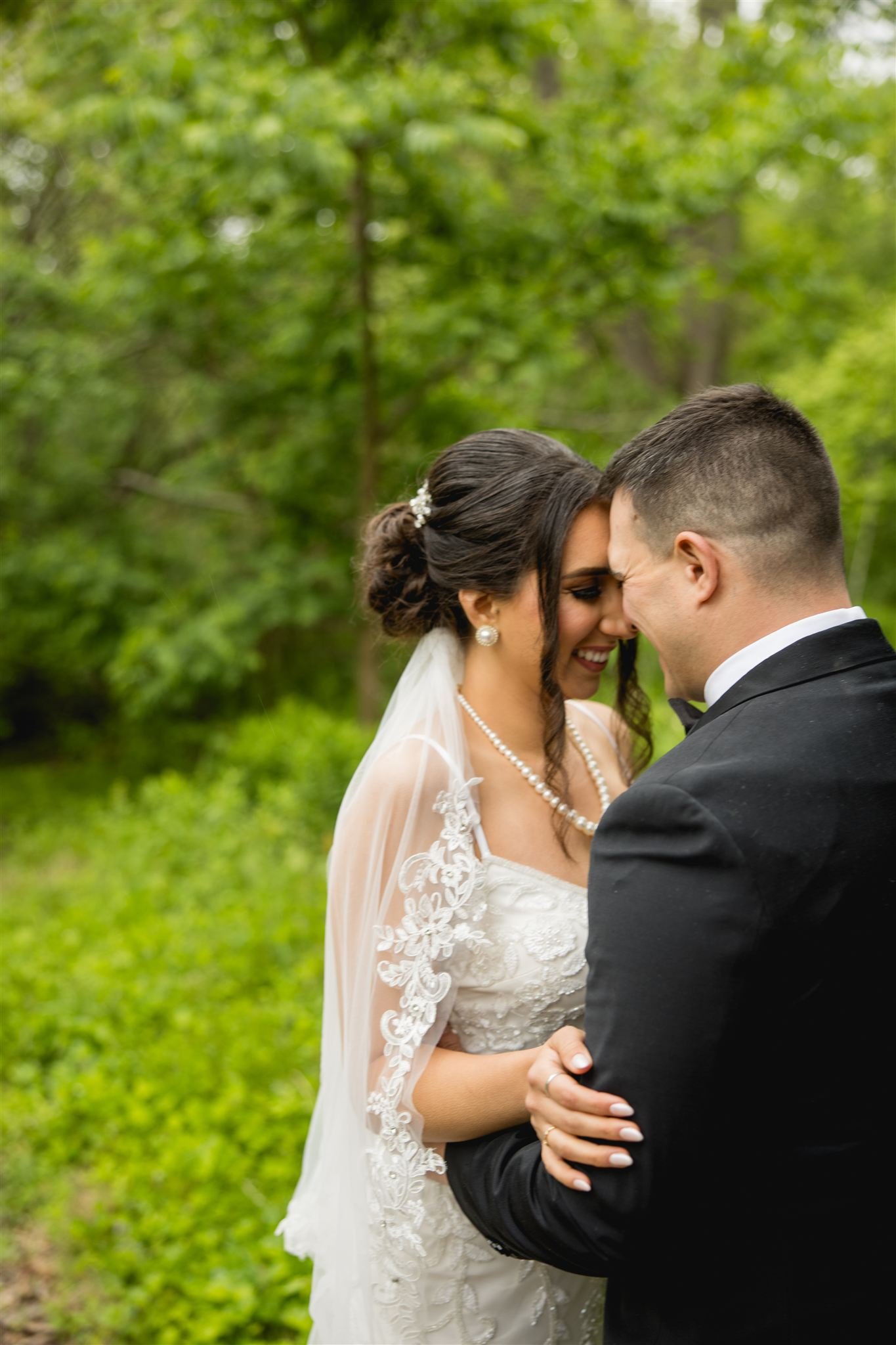 bride and groom smiling and sharing an embrace amongst the foliage of an outdoor micro wedding at Arnold's Arboretum in Jamaica Plains Boston