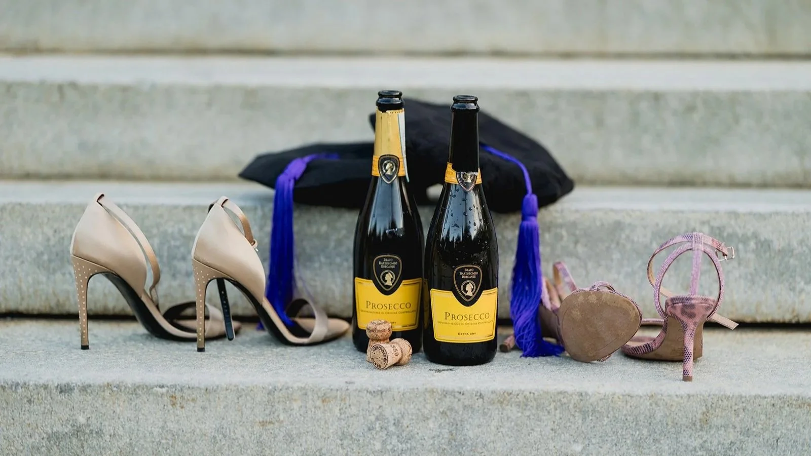 Details of a successful Boston College graduation celebration including two pairs of heels, graduation caps, and champagne bottles